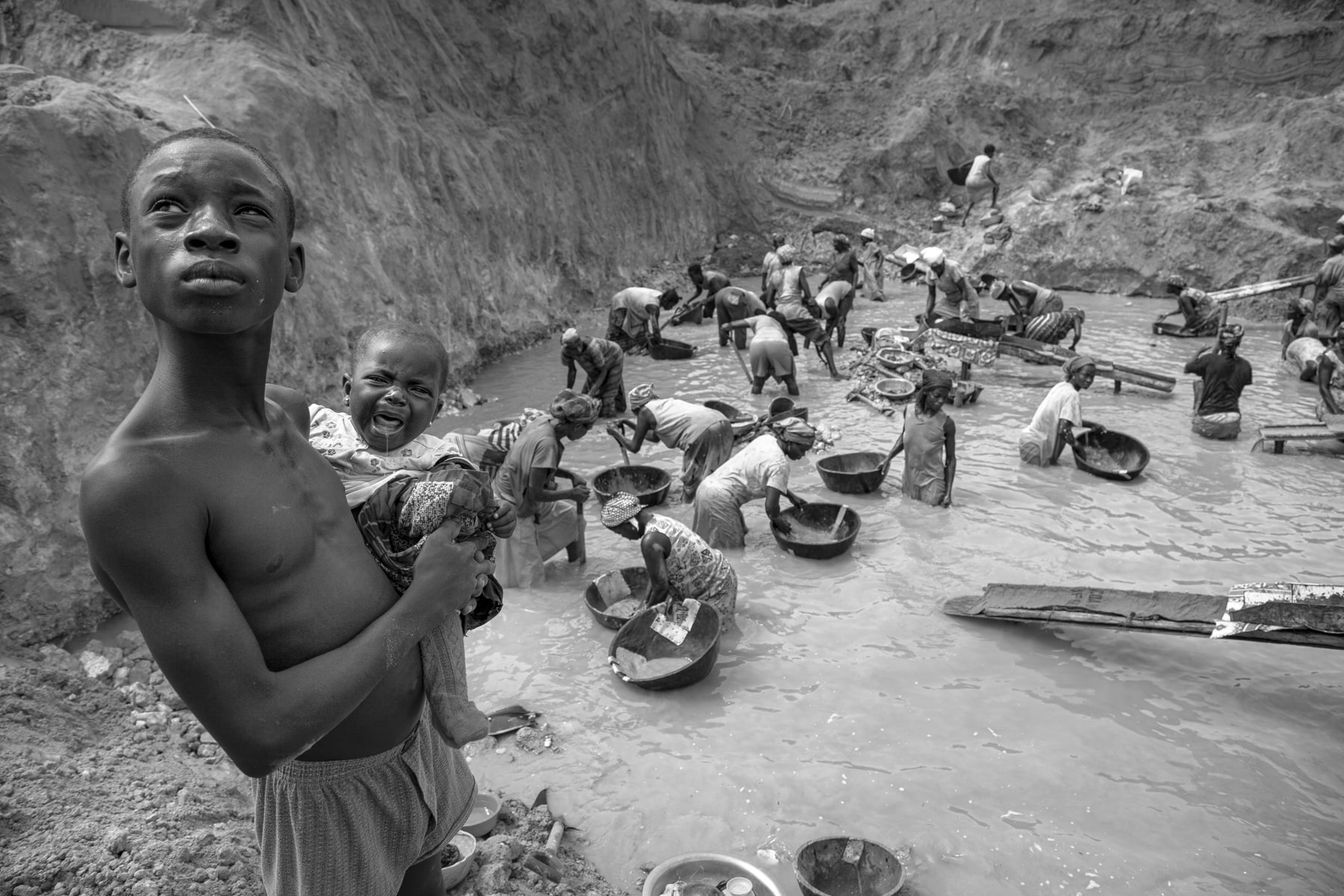 Boy carrying a crying baby in Ghana