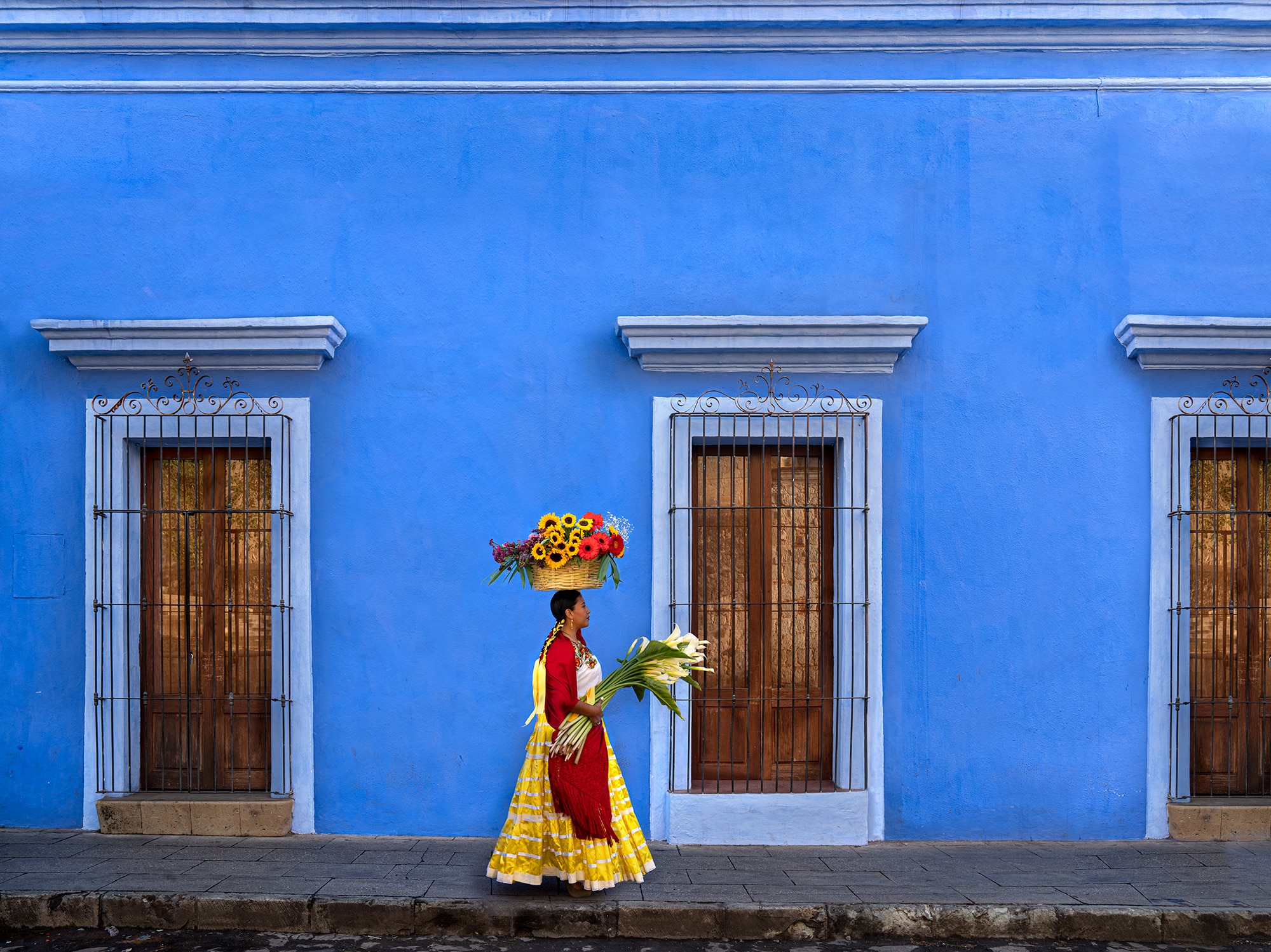In Oaxaca, a woman carries flowers (flores) to the market.