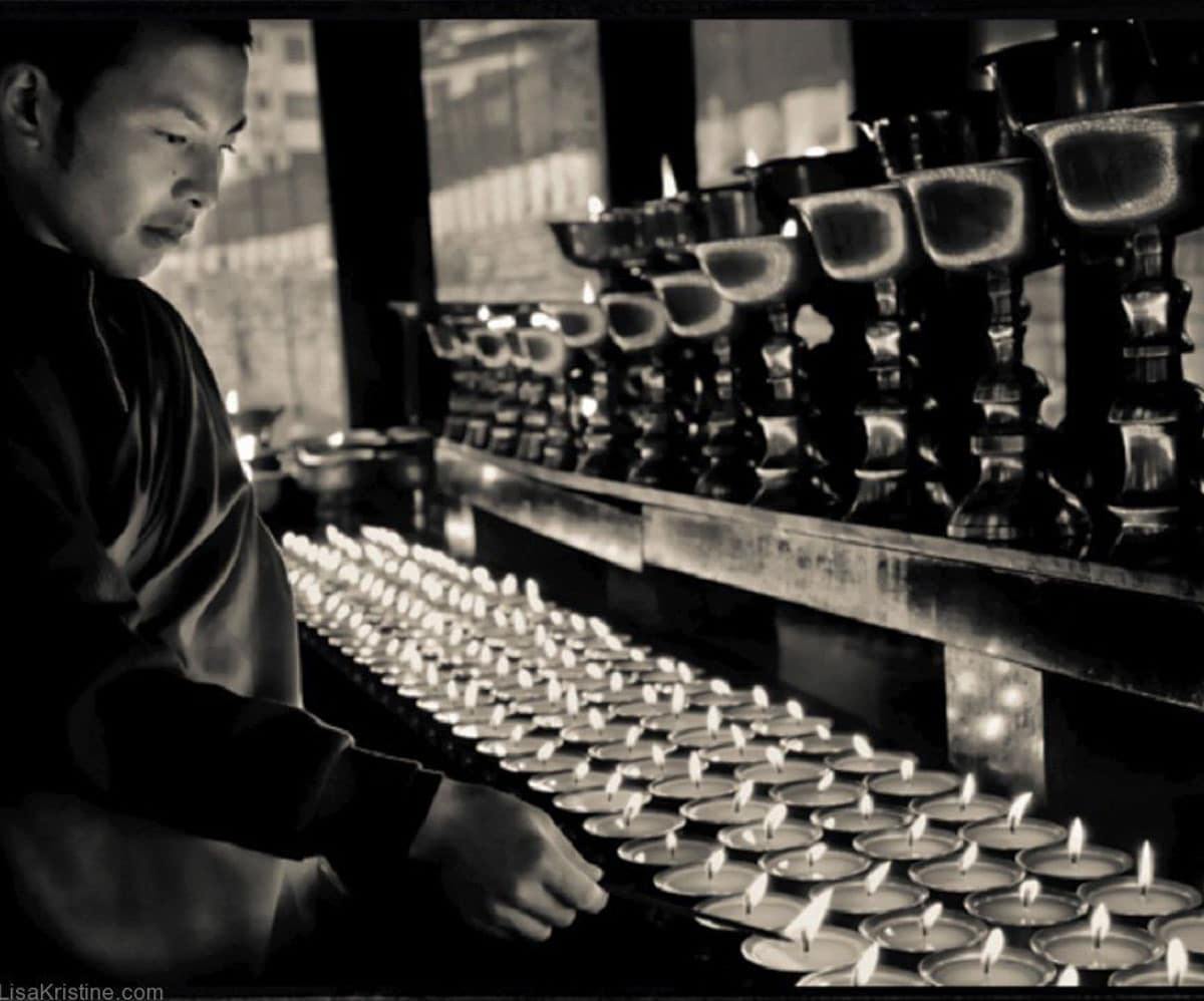 A man sitting with hundreds of candles lit in front of him in Bhutan