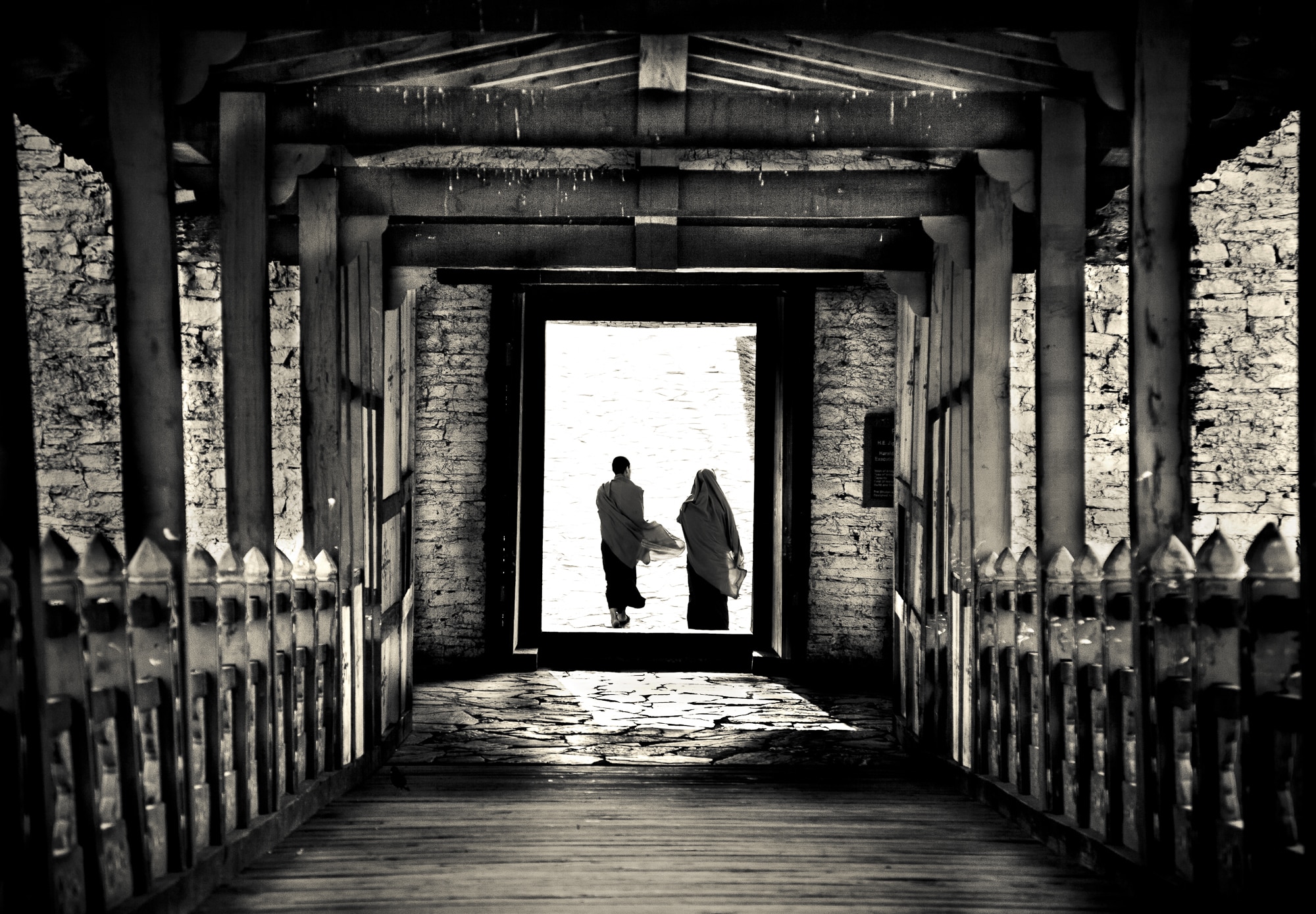 Two people walking over a bridge in Bhutan