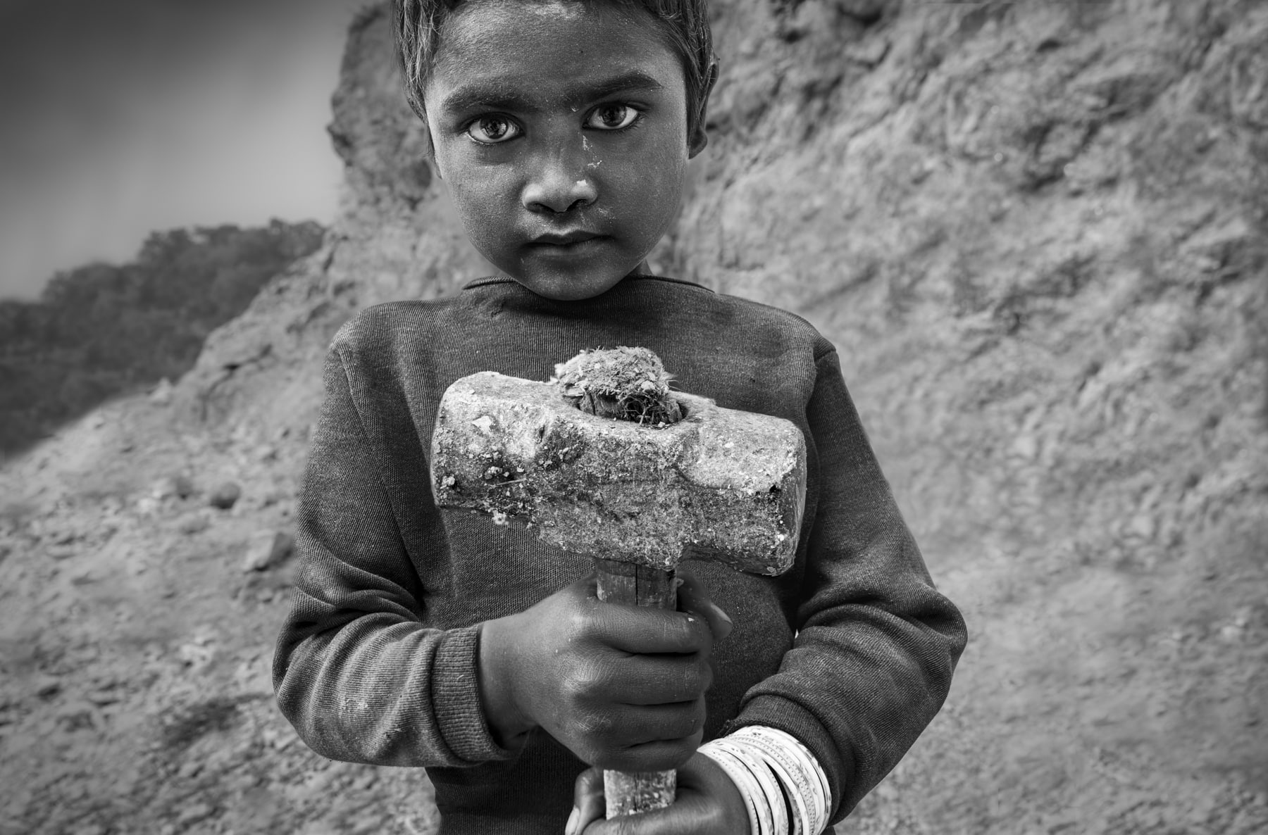 A laborer in India grips a sledgehammer, embodying the strength and determination of hard work in challenging conditions.