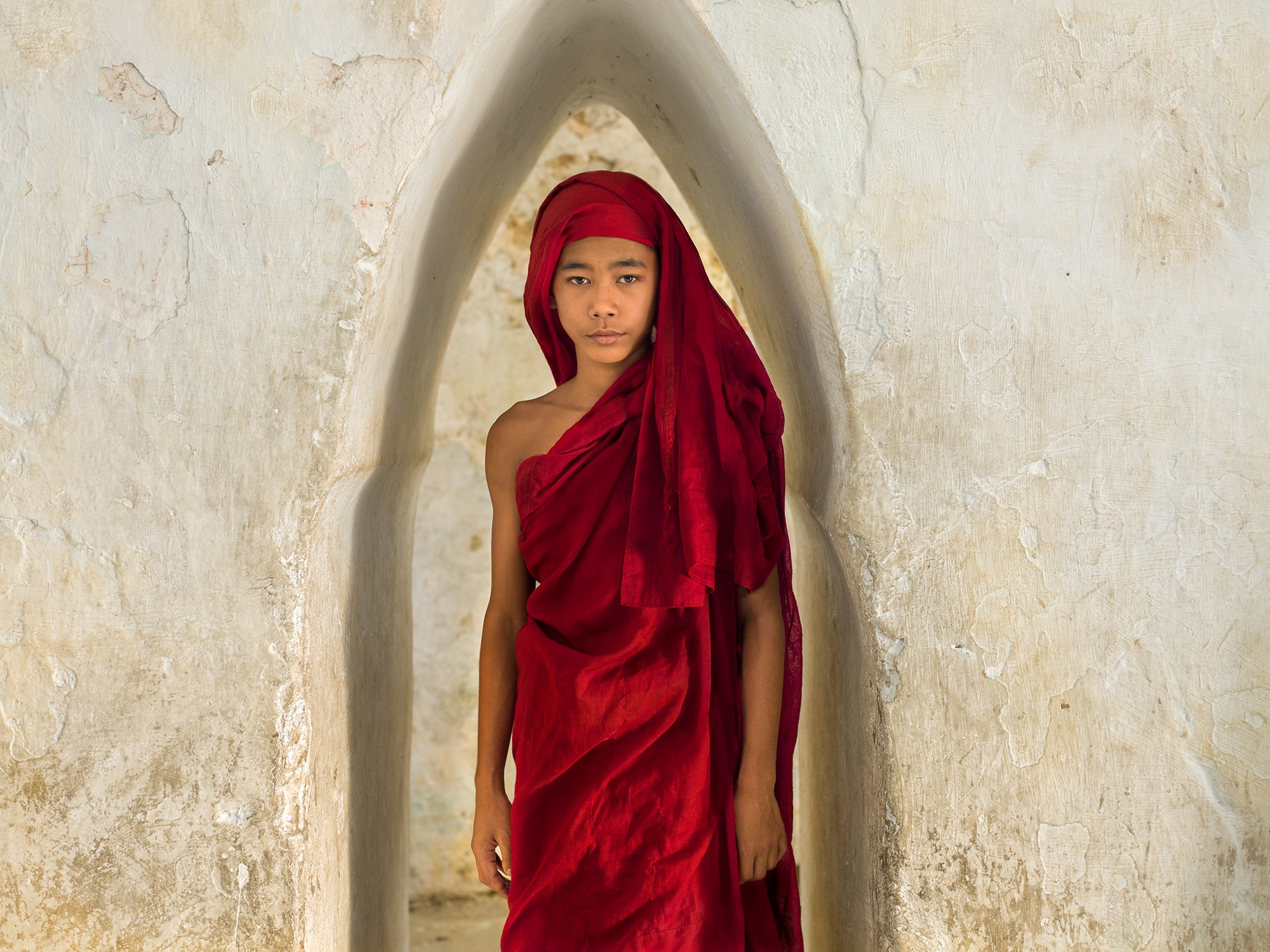 In this alcove of sculpted space that is a natural part of the architecture and leads to other areas, it seems to me this young monk is standing in the womb of the temple.