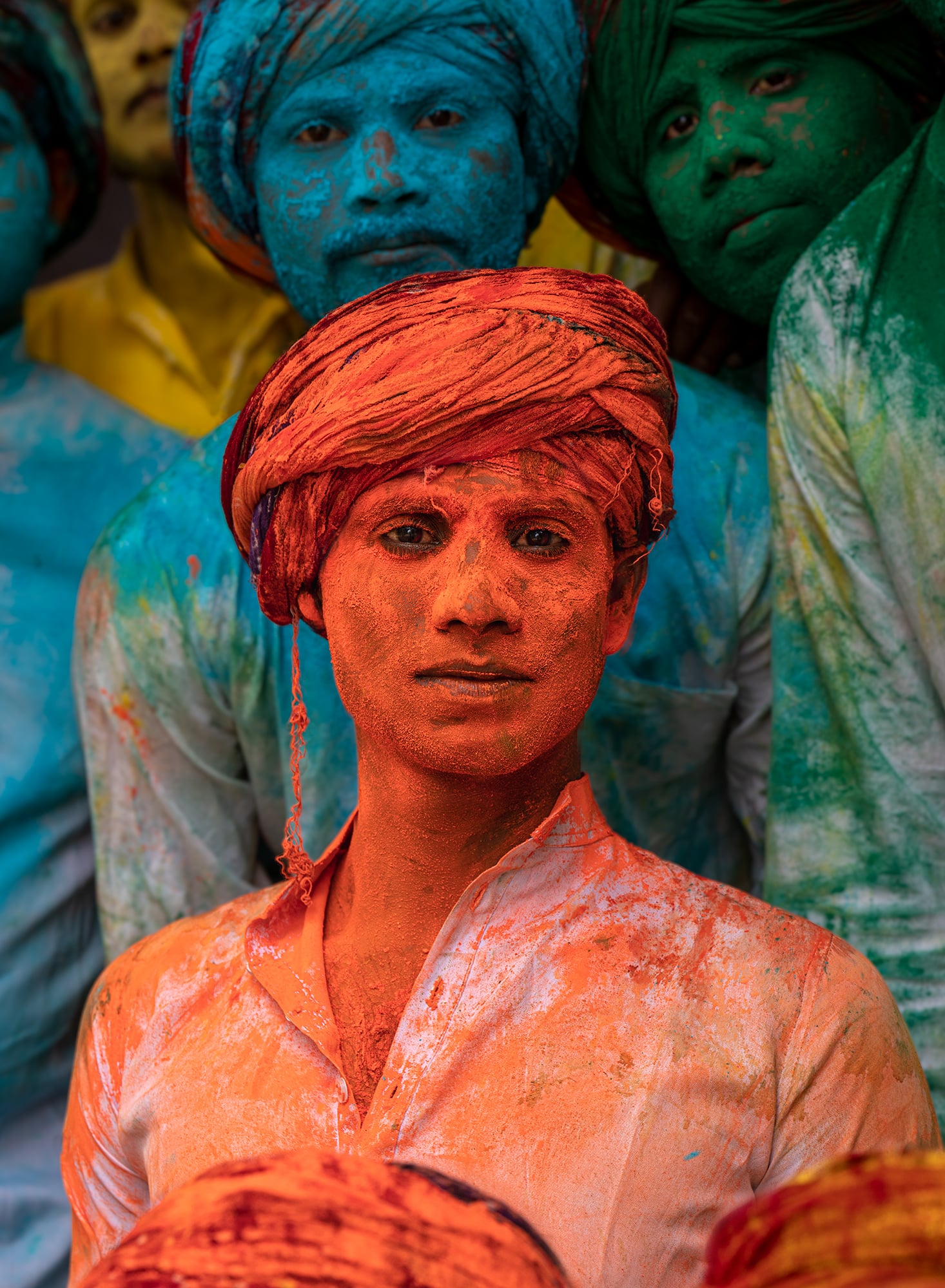 Young man at Holi in Bal Ashram, India with distinct red-orange coloration.