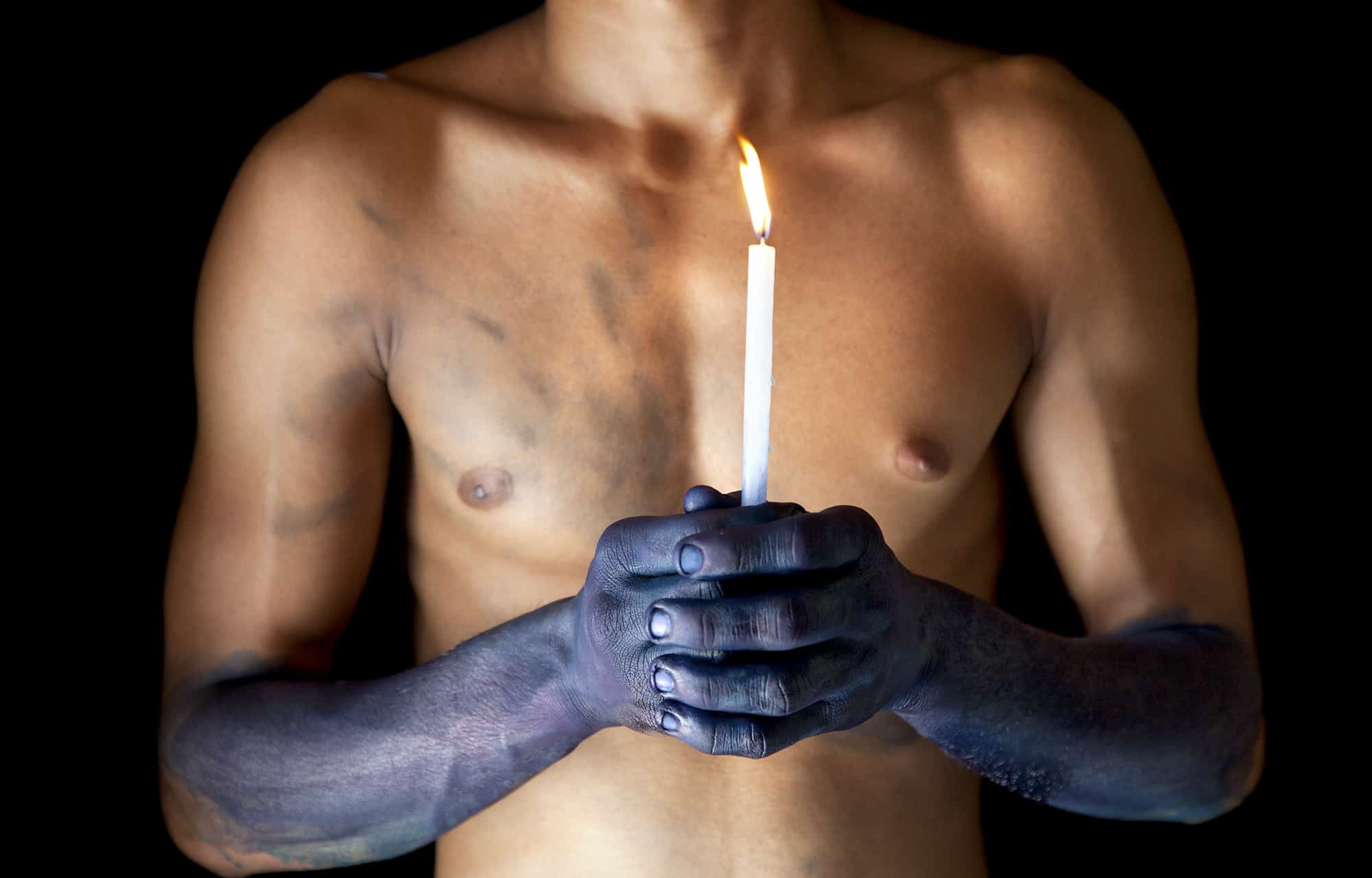 Hands died blue holding a candle in India